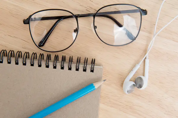 Ноутбук с карандашом, наушником и очками на столе — стоковое фото