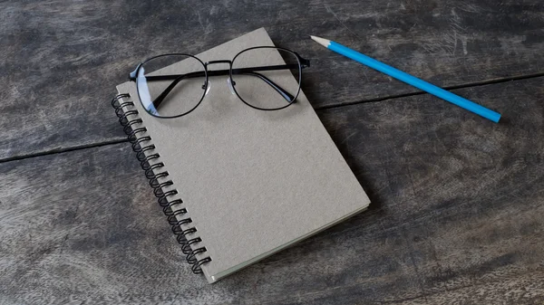 Натюрморт белый блокнот, карандаш и очки на столе — стоковое фото