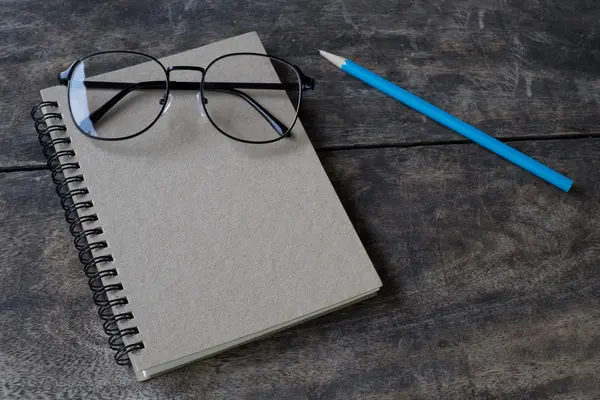 Натюрморт белый блокнот, карандаш и очки на столе — стоковое фото
