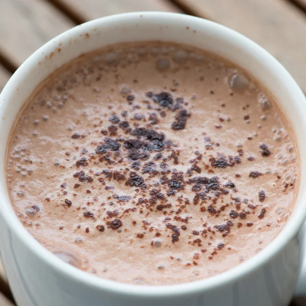 Warme chocolademelk in een witte kop op tafel — Stockfoto