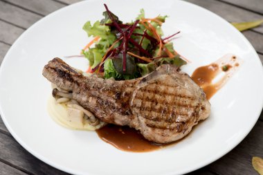 koyu ahşap zemin üzerine sebzeli t-Bone biftek