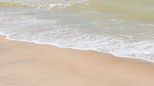 Zelené oceánu vlnu s bílým pískem na pozadí — Stock fotografie