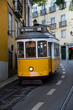 Lizbon, Portekiz 'de dik, dar ve kaldırımlı bir caddeye tırmanırken klasik, sarı renkli bir tramvay (özellikle 