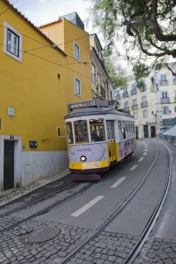 Lizbon, Portekiz 'de dik, dar ve kaldırımlı bir caddeye tırmanırken klasik, sarı renkli bir tramvay (özellikle 