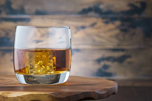 氷のキューブをガラスにした金色のウイスキーまたはバーボン ウィスキーやブランデーと木製のテーブルグラスで アルコール飲料 — ストック写真