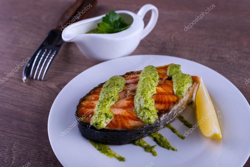 Salmon steak grilled with sauce chimichurri and lemon Stock Photo by