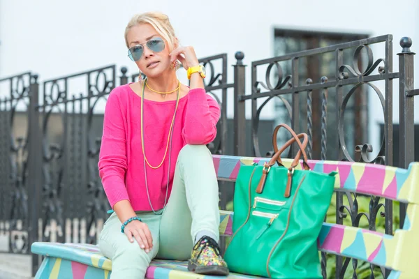 Street fashion mooie vrouw zittend op een bankje — Stockfoto