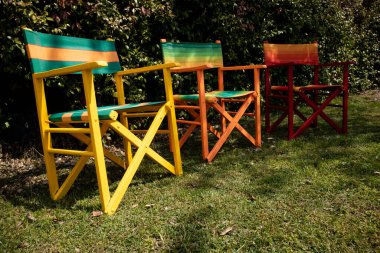 Rahatlama alanındaki bir bahçede küçük renkli ahşap sandalyeler.