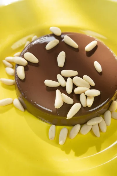 Photographic presentation of a vegan dessert, pudding with soy milk, cocoa and brown sugar and pine nuts