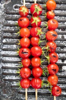Photographic representation of three skewers made with Pachino cherry tomatoes, Sicily Italy, juicy and tasty reds cooked on the plate 