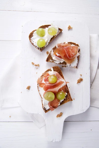 Bread, cheese and ham and grapes — Stock Photo, Image