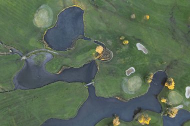 Sonbaharda bir golf sahasının havası, arazinin, göllerin ve yeşil çimlerin şeklini vurgulamak, canlı renkler ve doğal bir atmosfer.. 