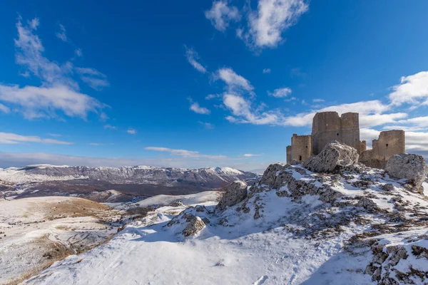 Rocca Calascio güneşli bir günde kar altında, arka planda Gran Sasso ve Monti della Laga Ulusal Parkı ve Abruzzo Campo Imperatore, İtalya 'da kış manzarası