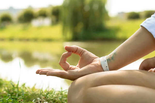 Closeup of the female hand put in gyan mudra. Woman sits on the grass at the river — Stock Photo, Image