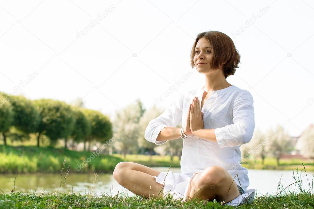 Woman with a serene look sitting on the grass in easy pose.