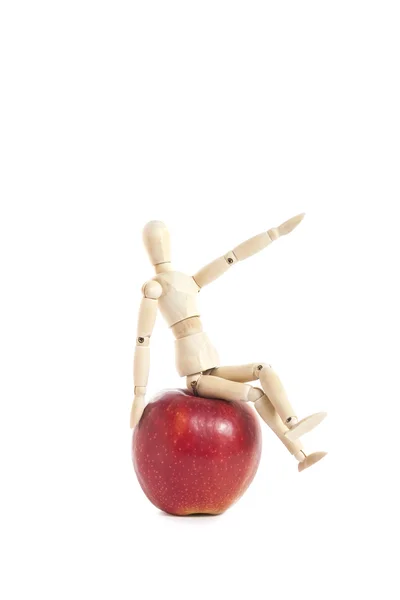 Apple üzerinde oturan neşeli ahşap oyuncak bebek — Stok fotoğraf