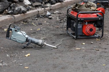 Benzin jeneratörlü elektrikli matkap tamir edilen bir yol bölümünün arka planına karşı çalışmaya hazır, boşluğu kopyala.