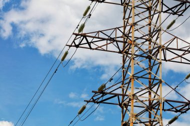 Yüksek voltaj elektriği iletimi için dielektrik yalıtımlı bir metal direğin parçası açık bulutlu mavi gökyüzüne çarpıyor..