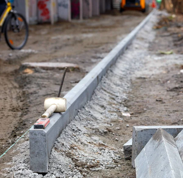 Construction of a bike path, concrete curbs anchored evenly along a tight thread against a blurred work area, selective focus, copy space.