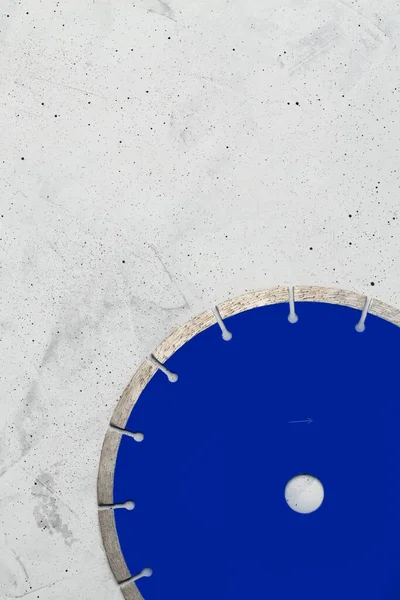 Blue cutting industrial blade with diamond for cutting concrete and reinforced on a gray concrete background. Vertical image, copy space.