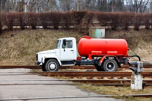 Sewage truck on pumping feces with a bright red cistern stands on the railroad tracks for disposal and cleaning at the rail road.