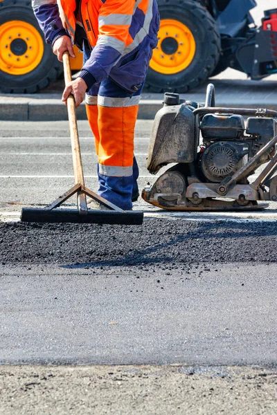 一个修路工人在一个压路机 压路机和平路机前面用木地板修理一段公路 垂直图像 复制空间 — 图库照片