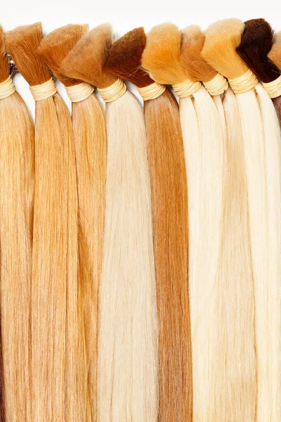 Bundles of natural healthy human hair in wheat shades. Hair care, style and beauty for women. Vertical image, copy space.