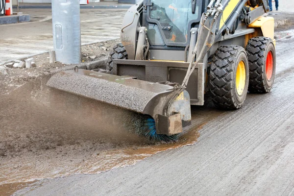 When repairing a road surface, a compact grader cleans dirt from the road to be repaired with a hydraulic nylon brush. Copy space.