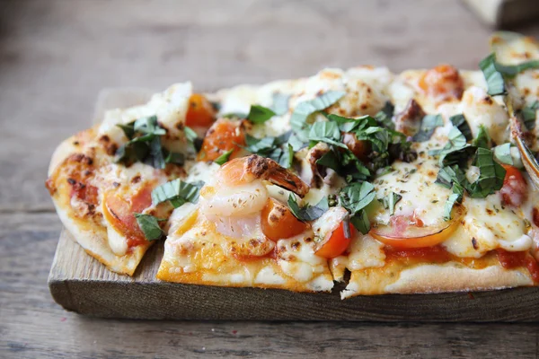 Pizza med skaldjur och tomater på ett träbord, italiensk mat — Stockfoto