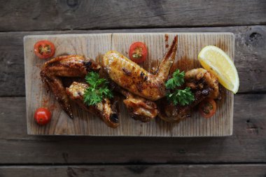 Ahşap arka plan üzerinde kırmızı baharatlı soslu ızgara tavuk kanadı
