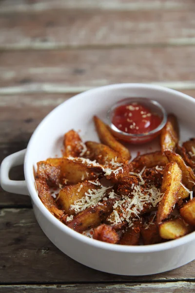Жареная картошка фри с кетчупом на деревянном фоне — стоковое фото