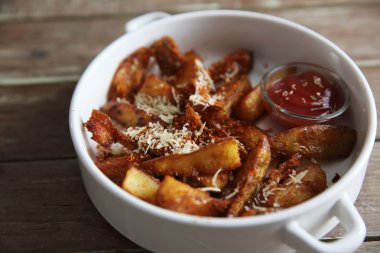 Tahta arka planda ketçaplı taze kızarmış patates kızartması.