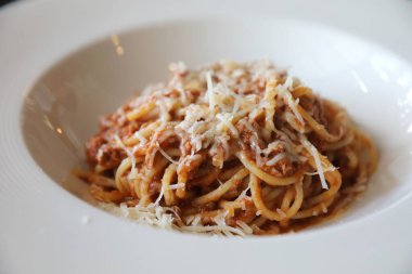 Parmesan peyniri ve fesleğenle süslenmiş kıyma ve domates soslu spagetti bolonezi. 