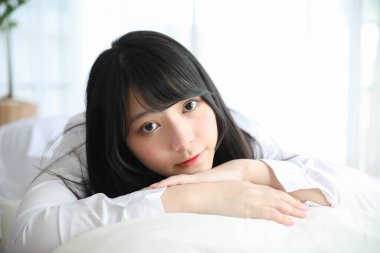 Portre güzel Asyalı kız beyaz odada yatakta uyuyor. 