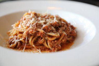 Parmesan peyniri ve fesleğenle süslenmiş kıyma ve domates soslu spagetti bolonezi. 