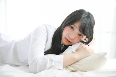 Portre güzel Asyalı kız beyaz odada yatakta uyuyor. 
