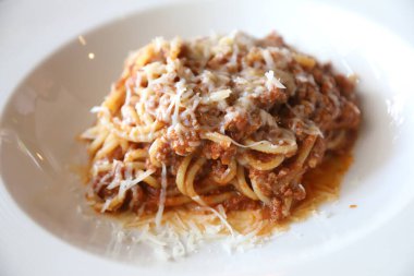 Parmesan peyniri ve fesleğenle süslenmiş kıyma ve domates soslu spagetti bolonezi. 