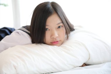  Liseli kız beyaz tonda yatak odasında uyuyor.