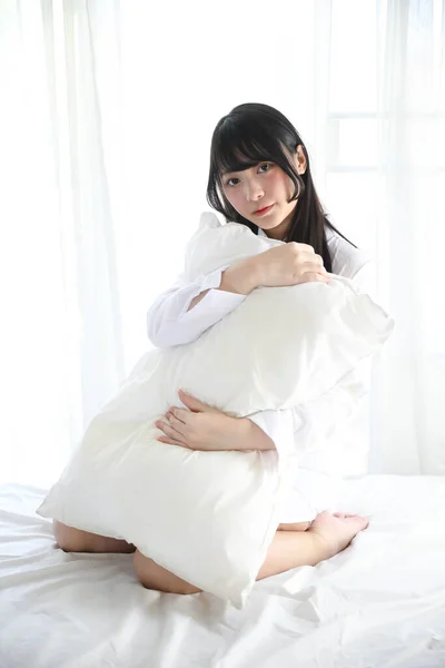 Mädchen Sitzt Mit Kissen Weißen Schlafzimmer — Stockfoto