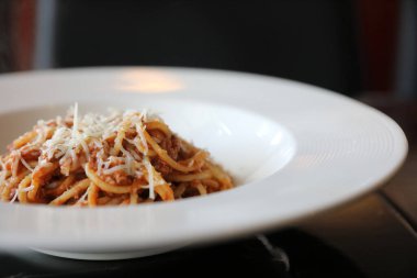Parmesan peyniri ve fesleğenle süslenmiş kıyma ve domates soslu spagetti bolonezi. 