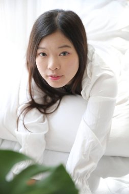 Kız beyaz yatak odasında yastıkla uyuyor.