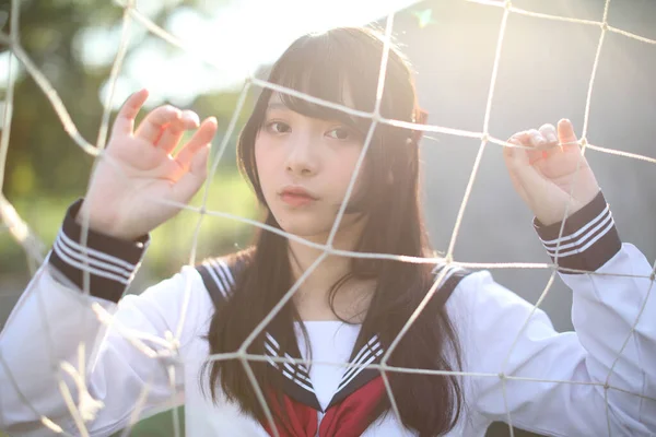 アジア系日本人女子高生の肖像 制服姿でサッカーゴールネット — ストック写真