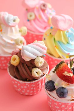 Pembe arkaplanda izole edilmiş renkli kekler