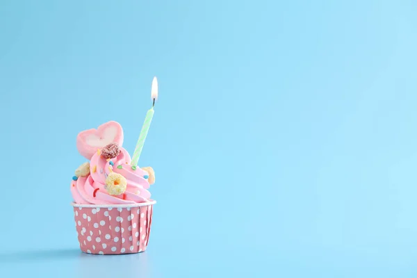 青い背景に隔離されたキャンドルとカラフルなカップケーキ — ストック写真