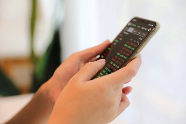 Akıllı telefon ile çalışan bir kadın kahve dükkanında hisse senedi ticareti, iş konsepti