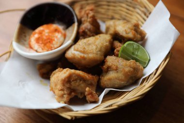 Ahşap zemin üzerinde limon ve sos olan Japon usulü kızarmış tavuk.