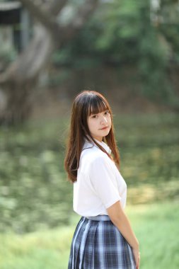 Güzel Asyalı Japon liseli kız üniforması parka bakıyor. 