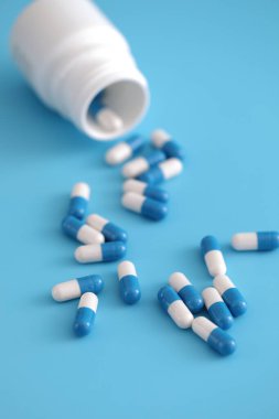 pills capsules with bottle isolated on blue background clipart
