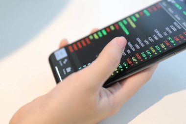 Akıllı telefon ile çalışan bir kadın kahve dükkanında hisse senedi ticareti, iş konsepti