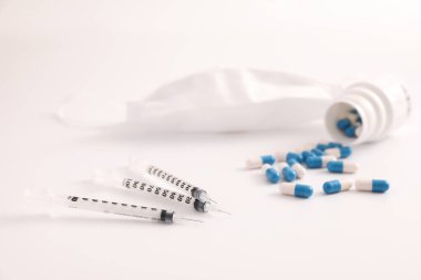 Beyaz arka planda izole edilmiş hap ve maskeli şırınga